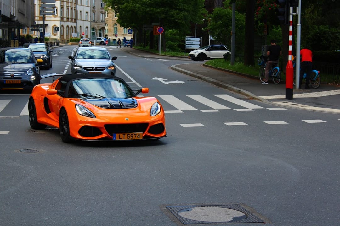 An orange sports car drives on a city street.